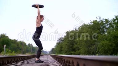 美丽的运动年轻的金发女人，穿着黑色的紧身裤，用一个沉重的盘子做运动，在上面。